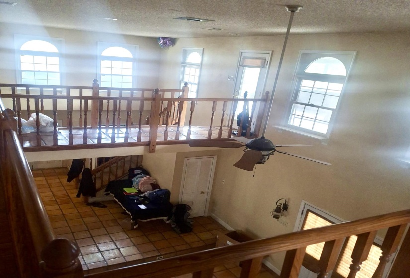 Stairway featuring ceiling fan, a textured ceiling, healthy amount of natural light, and tile patterned floors