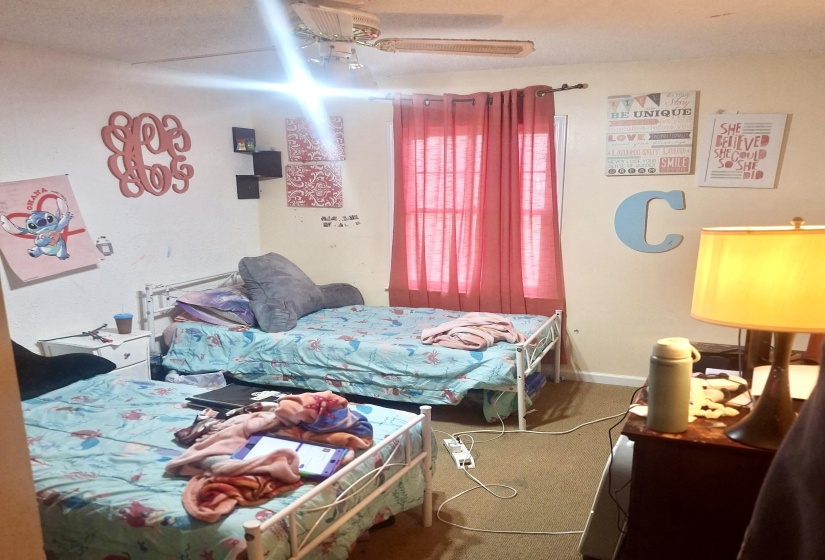 Carpeted bedroom featuring ceiling fan and baseboards