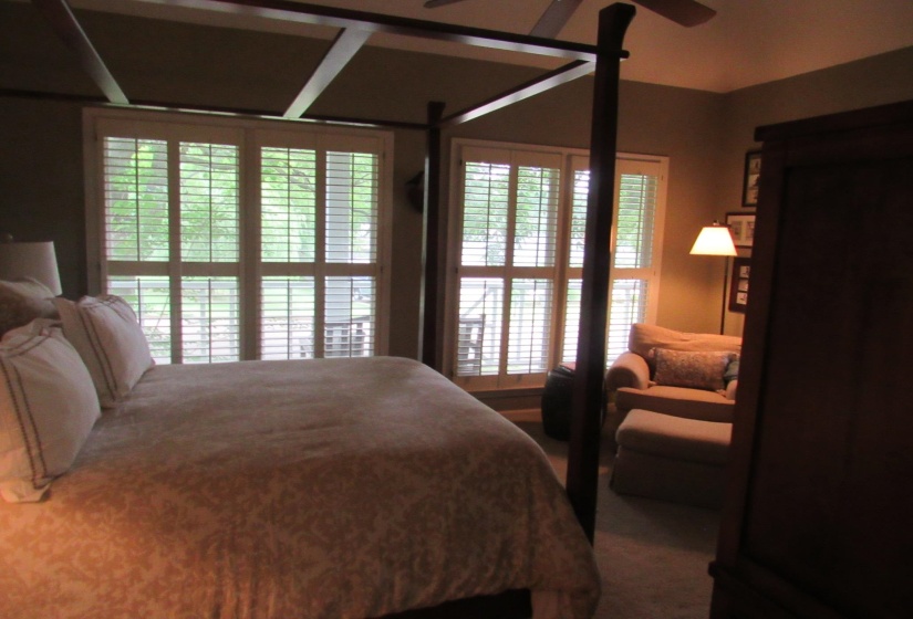 Room featuring plantation shutters on large windows, tray ceiling, and ceiling fan