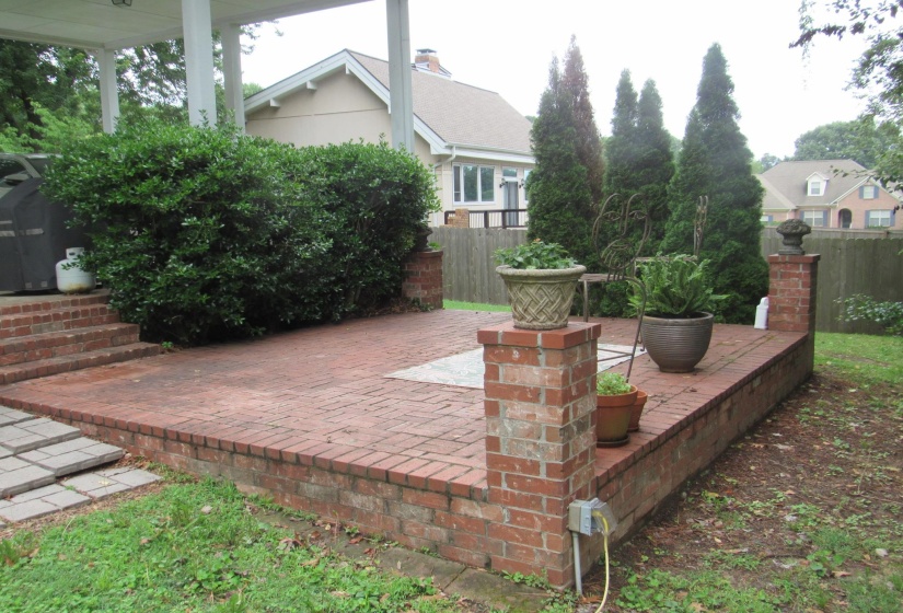 Elevated brick patio featuring a low brick retaining wall, integrated brick columns, and direct access to an exterior porch
