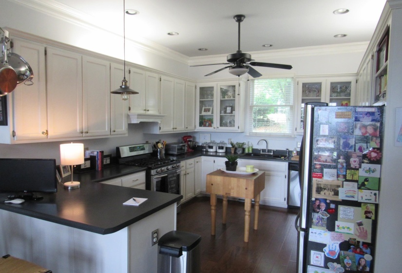 Well-appointed kitchen featuring abundant white cabinetry, dark countertops, recessed lighting, wood-finish flooring, and a ceiling fan