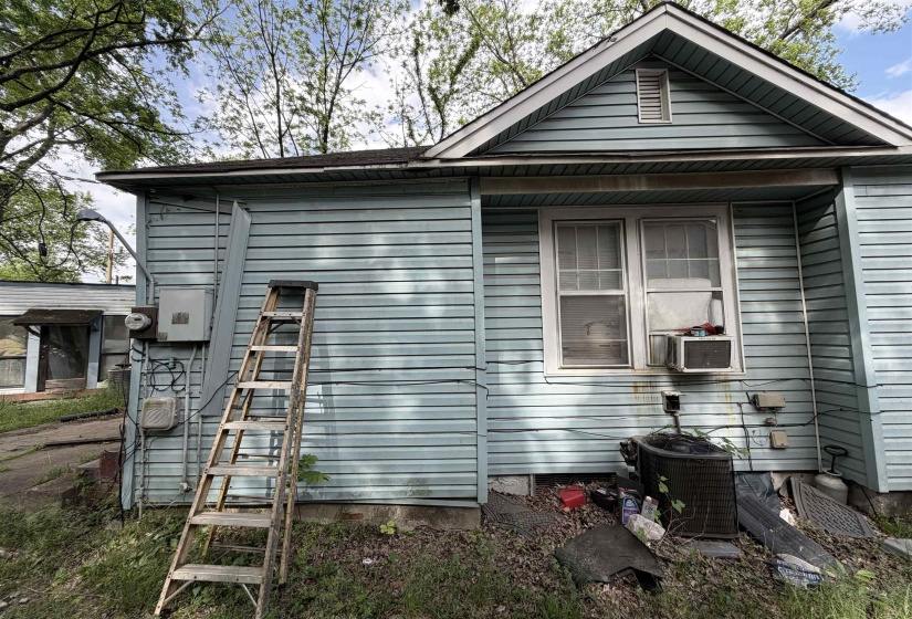 Light blue horizontal siding on exterior, featuring a white-framed window and a gable vent