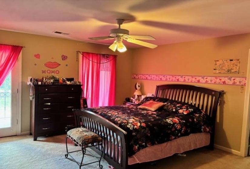 Bedroom with light colored carpet, ceiling fan, and access to balcony