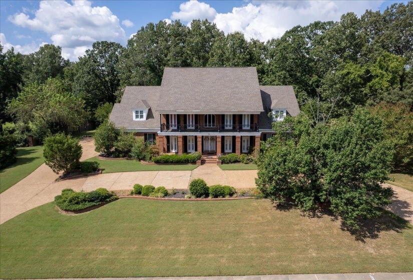 View of front of home featuring a front yard, a porch, brick siding, a balcony, and driveway