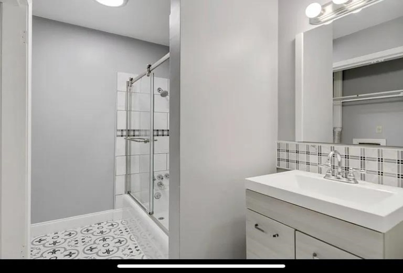 Bathroom featuring a glass-enclosed tub/shower combo with subway tile surround and a decorative accent band