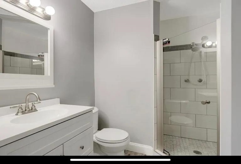 Bathroom featuring a single vanity with storage cabinetry, integrated sink, and brushed nickel faucet