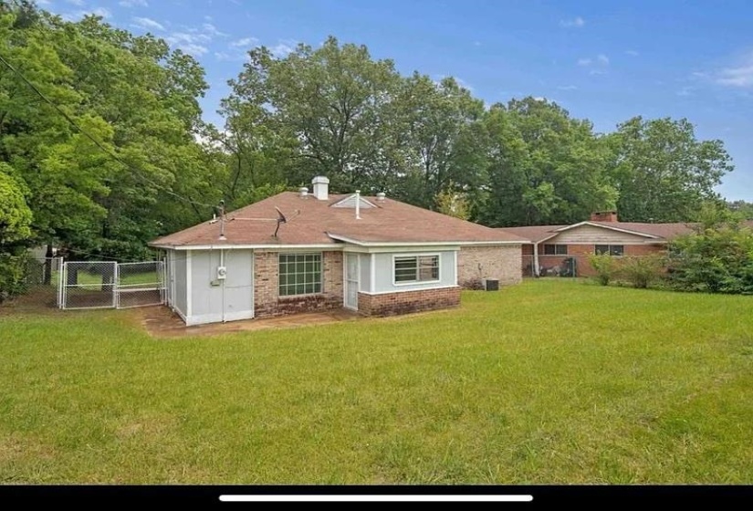 Expansive lawn surrounding a brick residence with a fenced enclosure