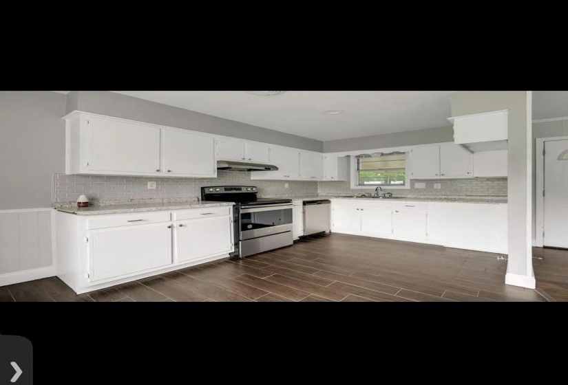 Kitchen featuring wood-finish flooring, white cabinetry, speckled countertops, subway tile backsplash, and stainless steel appliances