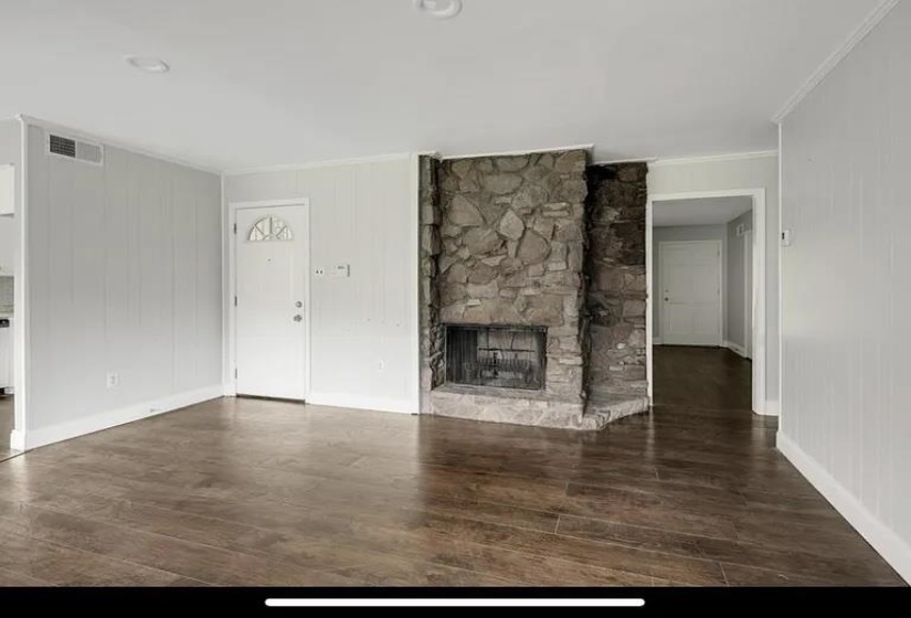 Living area featuring a floor-to-ceiling stone fireplace, wood-finish flooring, white paneling, and recessed lighting