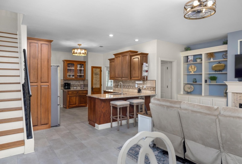 Open-concept living area with tile flooring and a staircase featuring wood treads and a black wrought iron railing