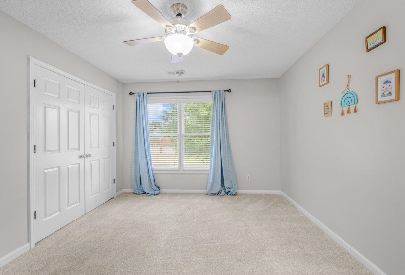 Neutral-toned room featuring a window with blinds, ceiling fan with light fixture, light gray walls, and light-colored carpet