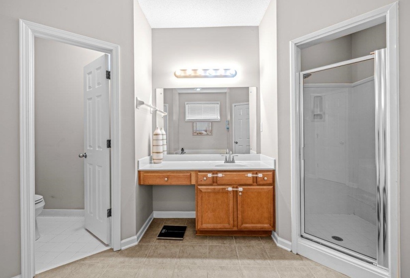 Bathroom vanity featuring wood cabinetry, white countertop, and a mirrored wall