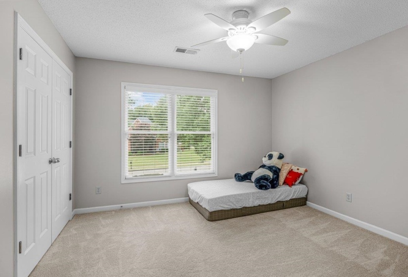 Neutral-toned room featuring a double window with blinds, a ceiling fan with integrated lighting, and a double-door closet