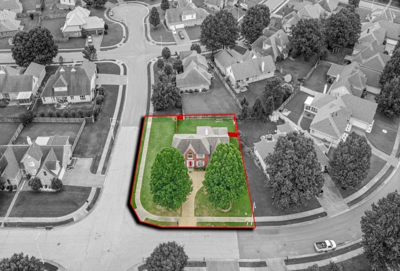 Aerial perspective showcasing a corner lot property with a red brick residence