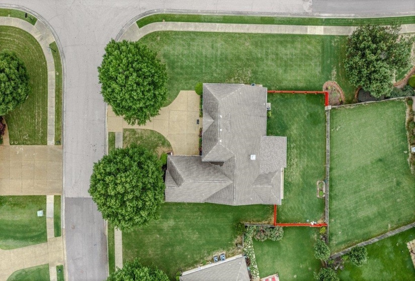Expansive corner lot featuring a multi-gabled roofline, concrete driveway, and established trees