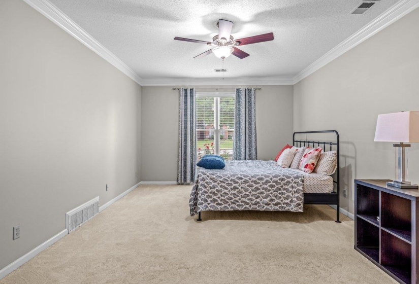Spacious interior room featuring light neutral wall paint, white crown molding, and carpeted flooring