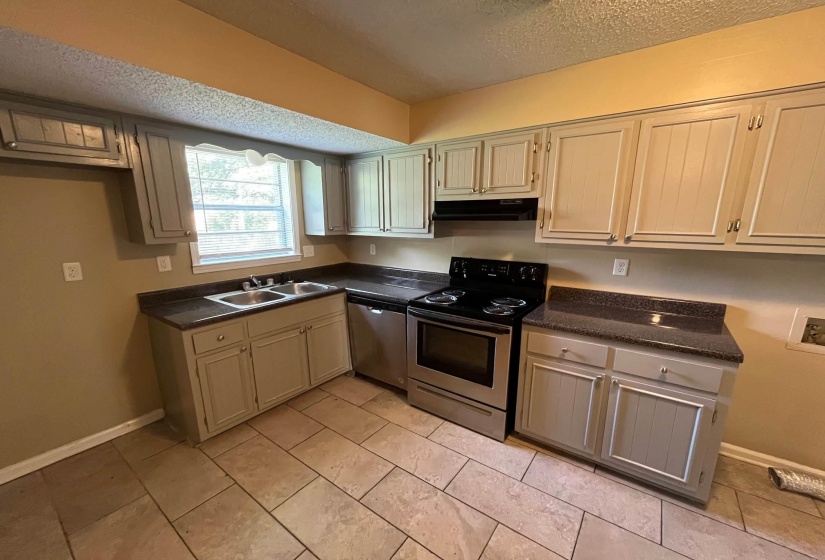 Kitchen featuring light-colored cabinetry with silver-tone hardware, dark speckled countertops, and tile flooring