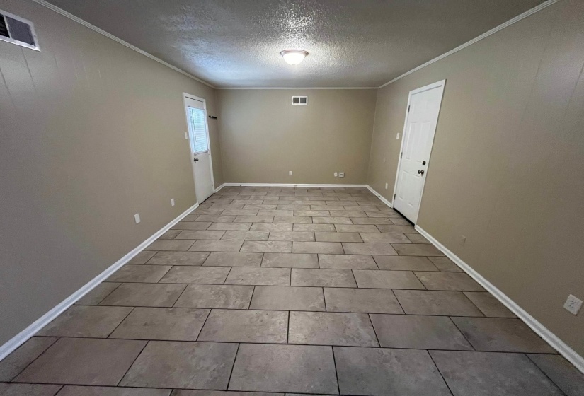 Spacious room featuring durable tile flooring, neutral wall paint, and white trim