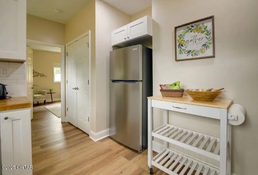 Kitchen area featuring wood-finish flooring, white cabinetry, and stainless steel appliances