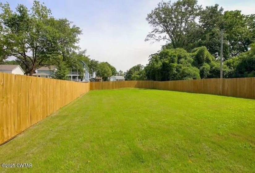 Expansive lawn area with a perimeter wood privacy fence, offering a verdant setting