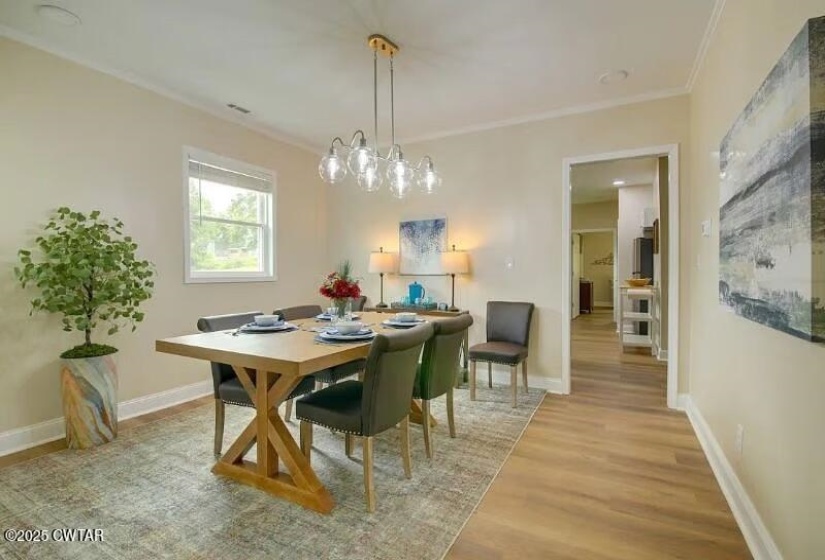Dining area featuring wood-finish flooring, a contemporary chandelier, and a window for natural light