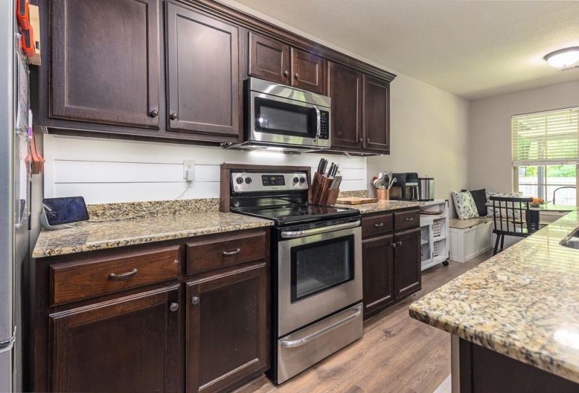 Kitchen featuring wood-finish flooring, dark wood cabinetry, and speckled countertops