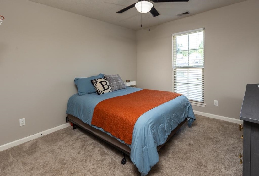 Bedroom featuring neutral wall paint, carpet flooring, a window with horizontal blinds, a ceiling fan with integrated lighting, and a built-in floating shelf