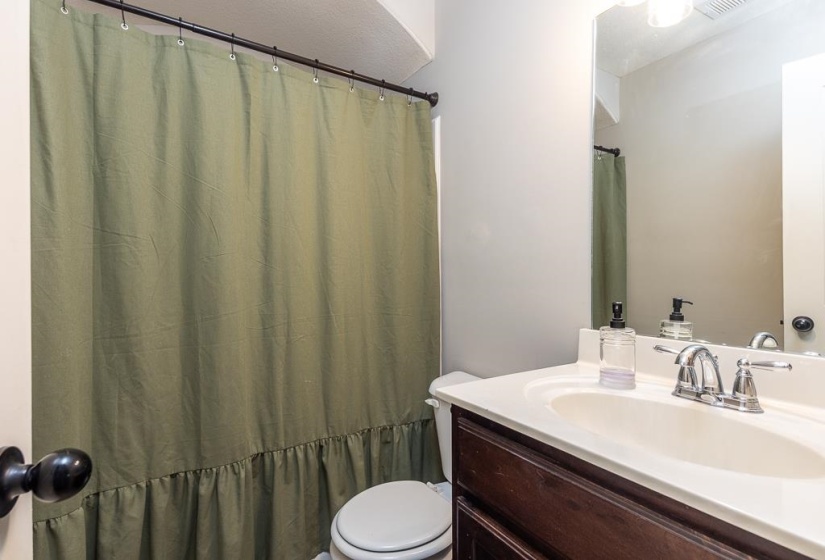 Bathroom featuring a single vanity with a white countertop and integrated sink, a dark wood-finish cabinet, and a chrome two-handle faucet