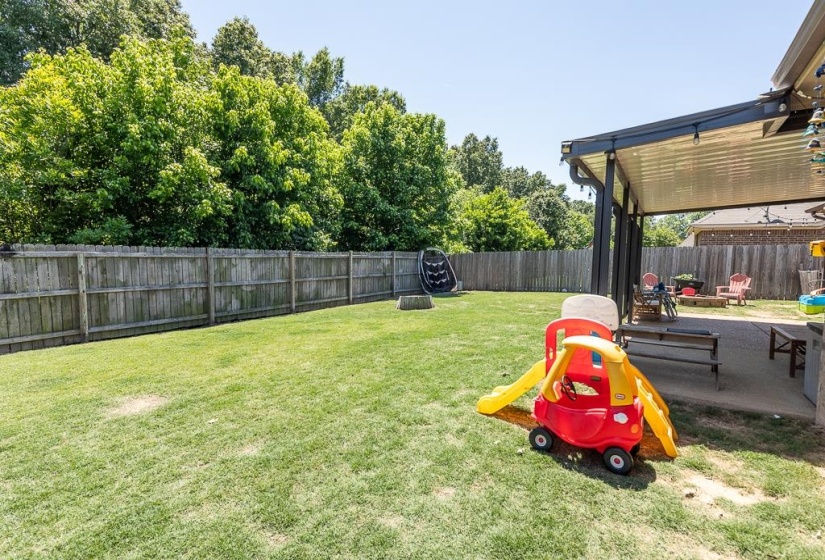 Expansive backyard featuring a manicured lawn, full privacy fencing, and mature trees