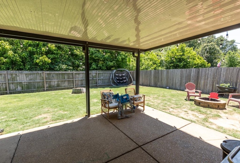 Covered patio featuring a concrete surface, overhead lighting, and direct access to a fenced backyard