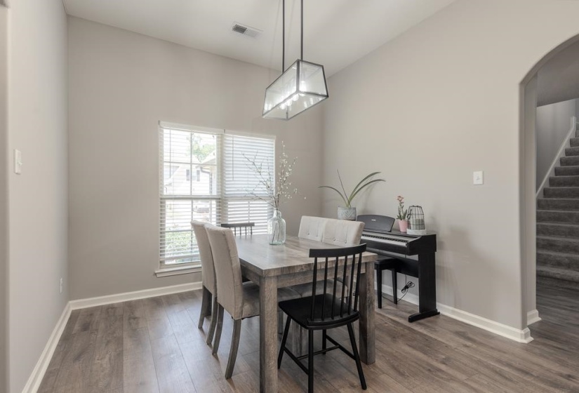 Dining area featuring wood-finish flooring, a contemporary geometric light fixture, and a large window with blinds