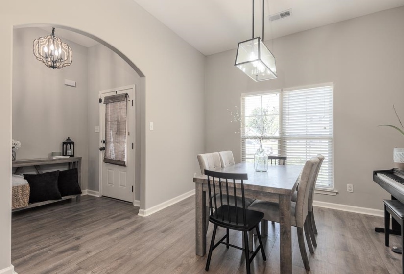 Dining area featuring wood-finish flooring, a large window with blinds, and an overhead geometric light fixture