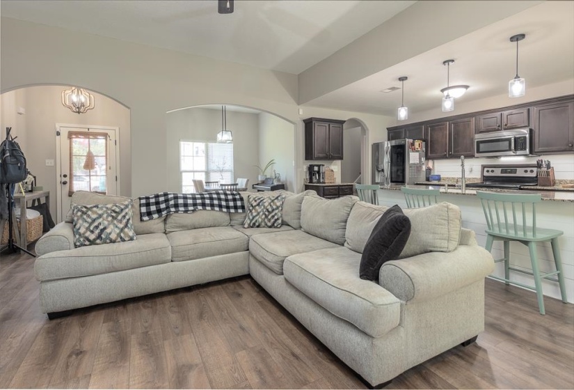 Open-concept living space featuring wood-finish flooring and a vaulted ceiling
