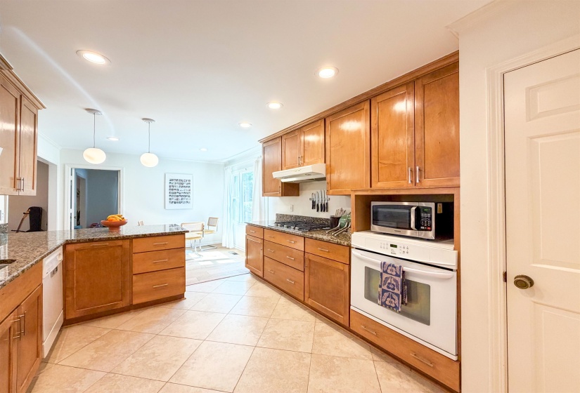 Kitchen featuring wood cabinetry, light-toned tile flooring, recessed ceiling lights, and stone countertops