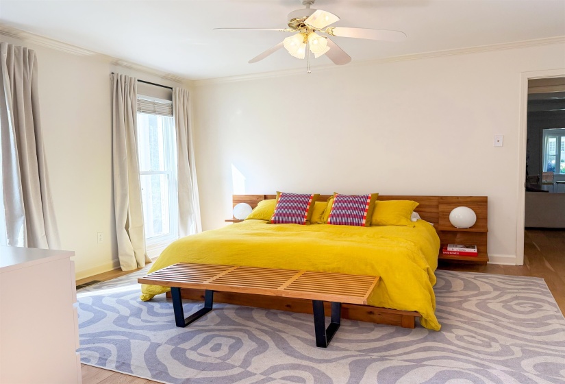 Spacious room featuring wood-finish flooring, crown molding, and a ceiling fan