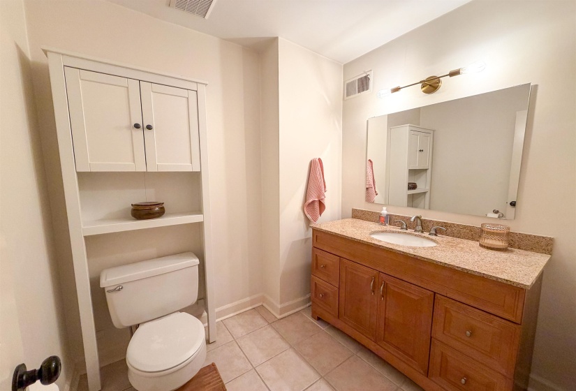 Bathroom featuring a single-sink vanity with a granite countertop, wood-finish cabinetry, and a framed mirror