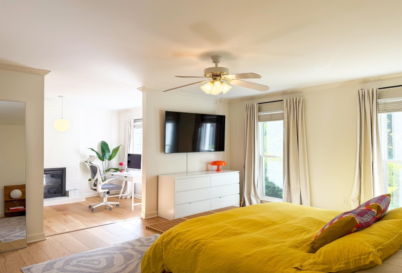 Open concept interior with wood-finish flooring extending into an adjoining space featuring a white brick fireplace