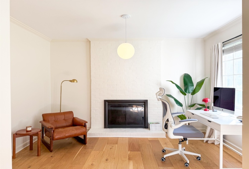 Warm wood flooring complementing a painted brick fireplace with a dark firebox