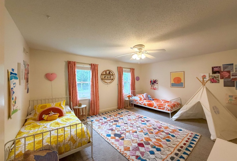 Spacious room featuring neutral walls, dual windows with natural light, and a ceiling fan for climate control