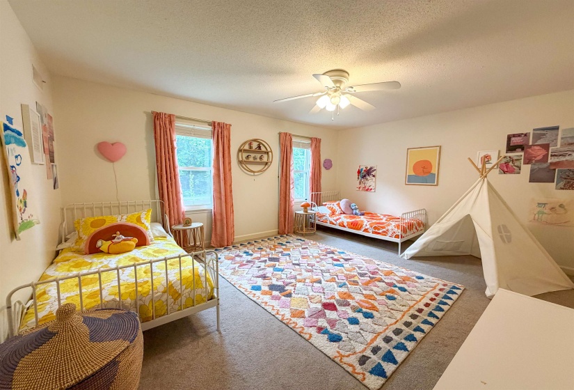 Carpeted room featuring a ceiling fan with integrated lighting, multiple windows, and light-toned wall finishes