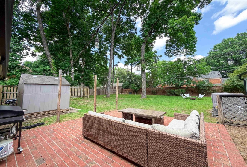 Brick paver patio with string lighting and a separate storage shed