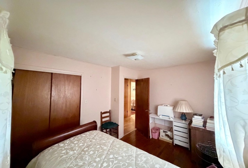 Interior room featuring wood-finish flooring, a wood door, and a built-in closet with sliding wood doors