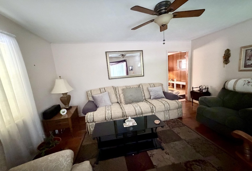 Interior room featuring wood-finish flooring, white walls, and a ceiling fan with light fixture