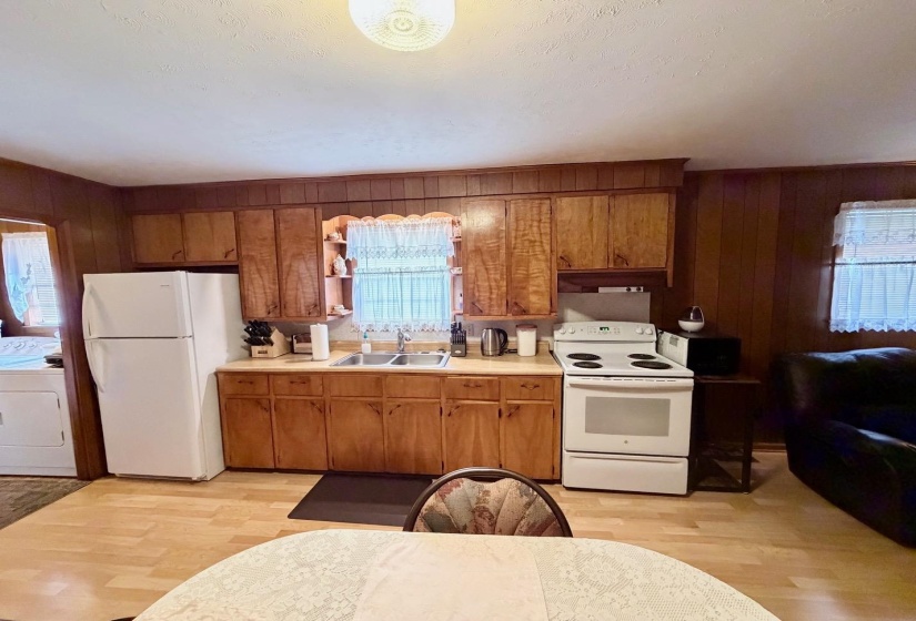 Kitchen featuring wood-finish flooring, wood cabinetry, a double basin sink, and white appliances including a refrigerator and range
