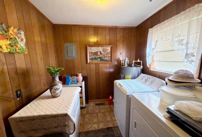 Utility room featuring wood paneling, a large window with blinds, and durable sheet vinyl flooring