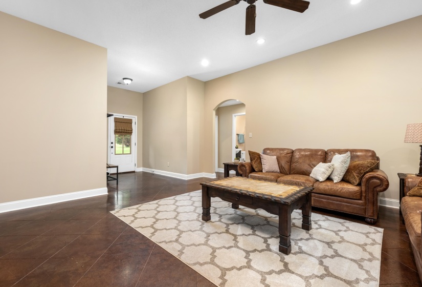 Spacious living area featuring dark wood-finish flooring, neutral wall tones, and recessed lighting
