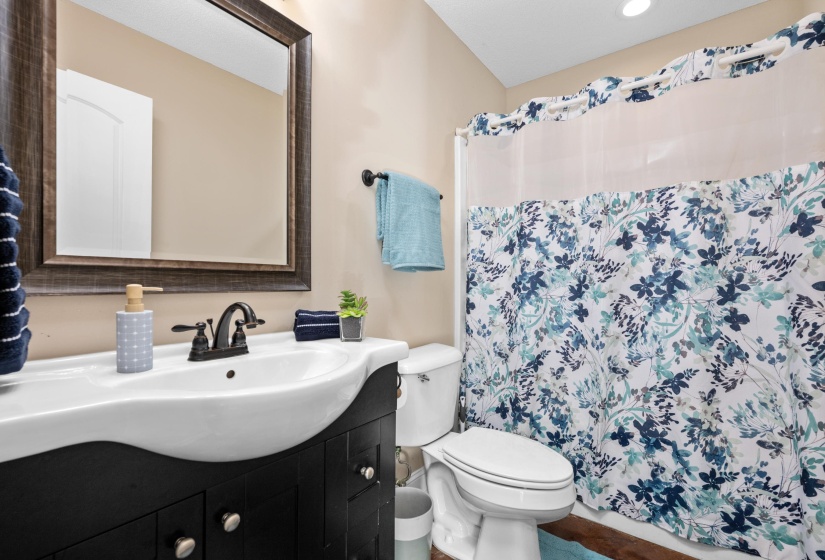 Bathroom featuring a dark wood-finish vanity with an integrated white sink, bronze-finish faucet, and coordinating wall mirror