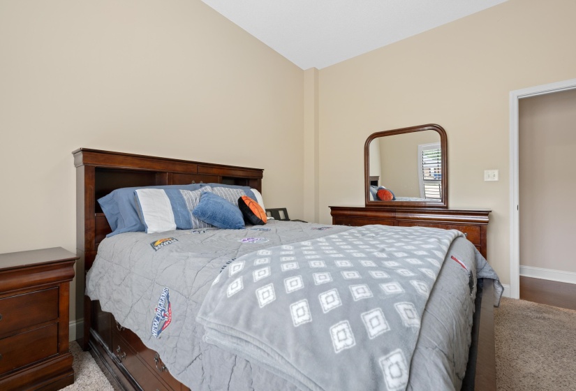 Carpeted bedroom featuring a vaulted ceiling and neutral wall tones