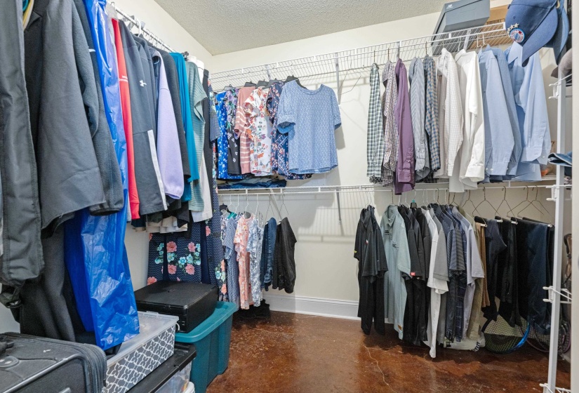 Walk-in closet featuring extensive wire shelving and multiple hanging rods, baseboard trim, and a textured floor