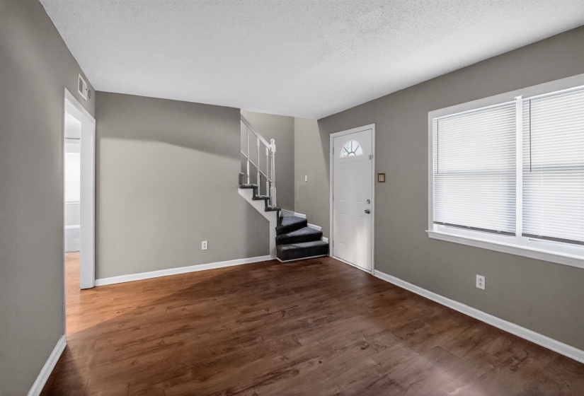 Spacious interior featuring wood-finish flooring, neutral gray wall paint, and white trim